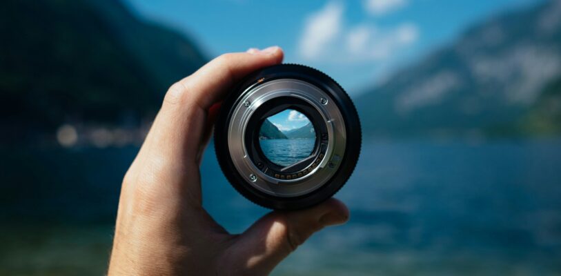 paul-skorupskas-7KLa-xLbSXA-unsplash Je ziet een landschapsfoto met in het midden een hand die een lens vasthoudt, waardoor je je focust op één punt in het landschap. Dit symboliseert het hebben en houden van een focus als je belegt.