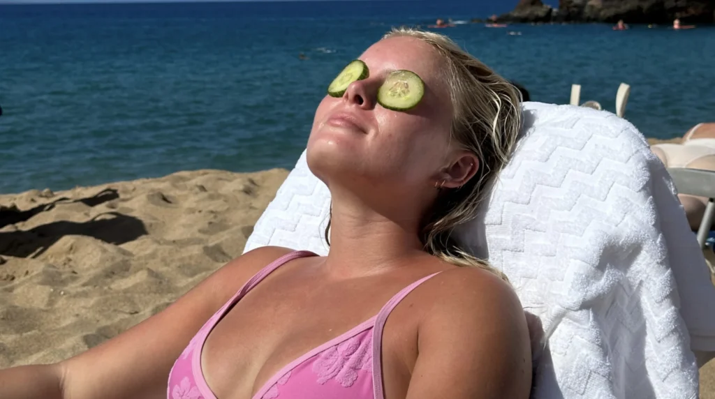 Vrouw in de zon met plakjes komkommer op haar ogen.