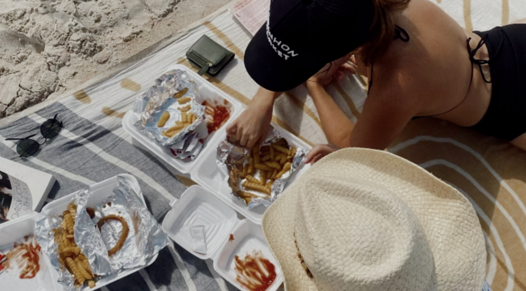 Vrouwen eten op het strand terwijl ze boeken over geld beluisteren